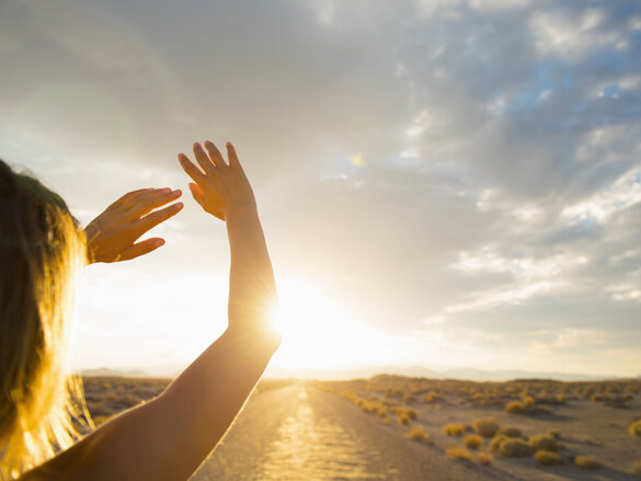 Hispanic woman shielding eyes from sun on remote road